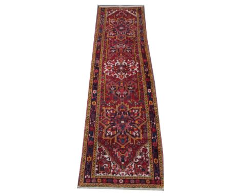 A Turkish wool runner, woven in red, yellow and blue dyes with three medallions surrounded by a floral motif border against a