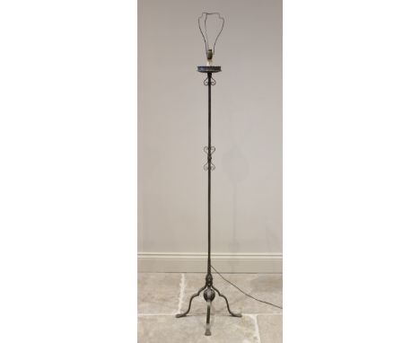 An early 20th century Arts and Crafts style wrought iron standard lamp, the square section column applied with scrolled detai