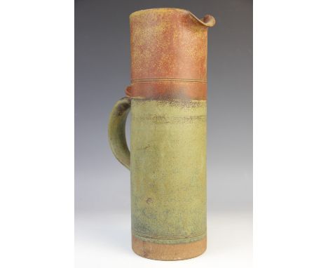 A Robin Welch (British, 1936-2019) cylindrical stoneware ewer, applied loop handle with thumbpiece, green and rust coloured b