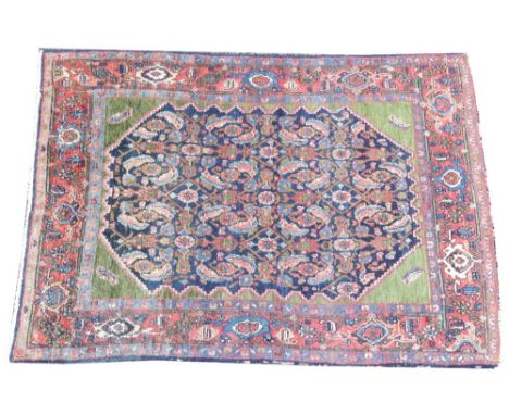 A Persian Village wool rug, the central panel with an abundance of repeating motifs, enclosed by green spandrels, within a fl