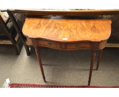 A reproduction figured walnut console table with shaped front, fitted two frieze drawers, raised on slender tapering reeded l