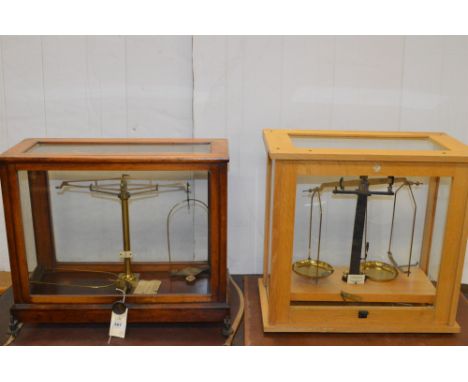 L. Gertling, London: a lacquered brass and mahogany glazed set of chemical balance scales; and another set of scales in oak c