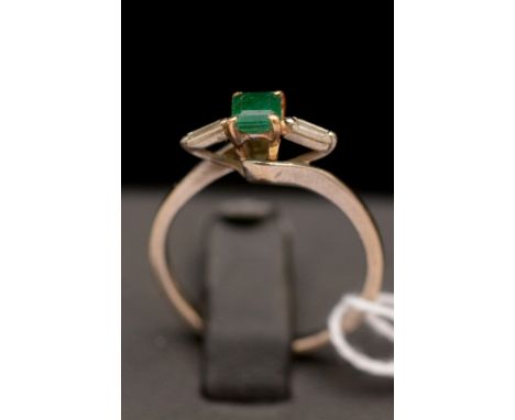 An emerald and diamond ring, the square cut emerald flanked by two baguette cut diamonds, on 18ct white gold shank.