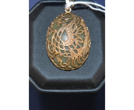 A jade coloured stone pendant mounted by 9ct yellow gold phoenix pattern mount.