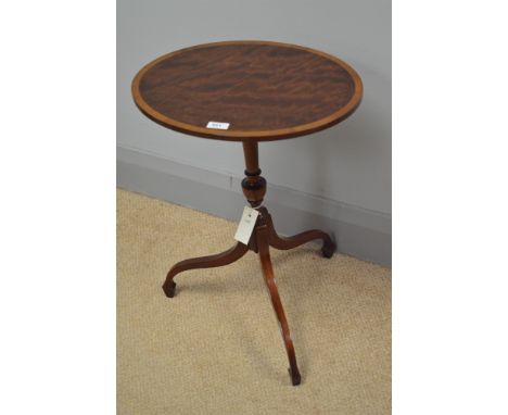 A reproduction mahogany oval wine table with crossbanded edge, raised on a turned column with three splayed legs, bearing a l