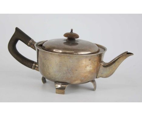An early Art Deco silver bachelors teapot, of plain squat circular form with angular wooden handle, the inset domed hinged co
