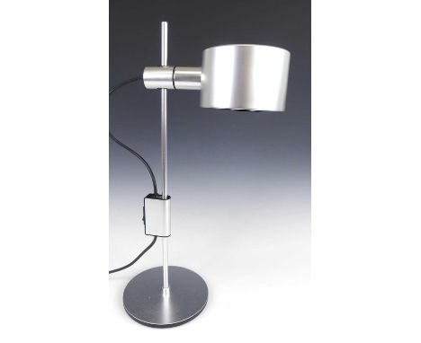 A contemporary brushed aluminium desk lamp, with rotating cylindrical shade and rise and fall action, to flattened circular b