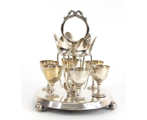 A circa 1900 silver plated six-person egg cup and spoon cruet set, comprising; a purpose-made two-tier stand with ornate cast