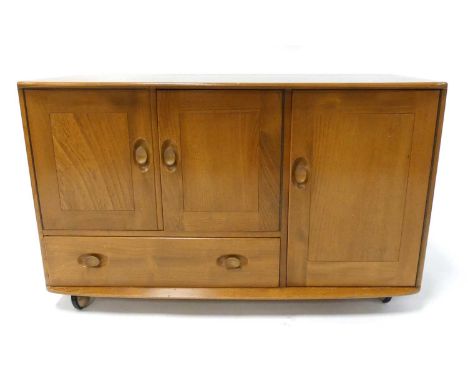 An Ercol blond elm Windsor 'Model 366' sideboard, having three cupboard doors and single lower drawer, raised on roller casto