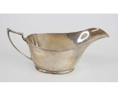 An Art Deco silver sauceboat, the oval body having everted rim and standing upon a shallow reeded footrim, having angular sha