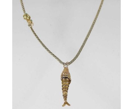 A gilt flexible link necklace, with a clasp in the form of a hand, wearing an emerald ring, 46cm long, suspended with an arti