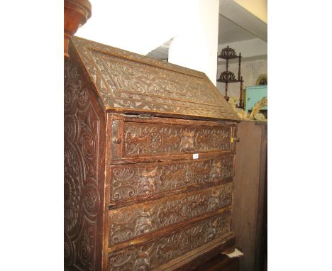 19th Century carved dark oak bureau with a fall front enclosing fitted interior, above four graduated drawers on bracket feet