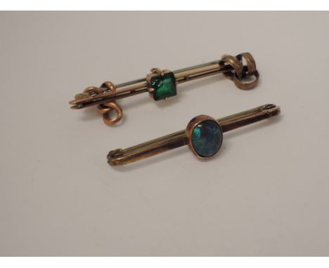 A yellow metal bar brooch stamped 9ct having a central oval black opal, another similar having a central green stone, and two