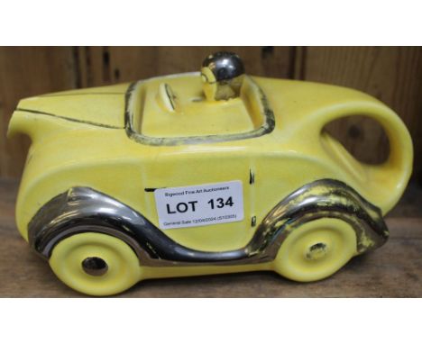 An Art Deco design sports car ceramic teapot, yellow glaze with silvered detail, number plate "OK T42"
