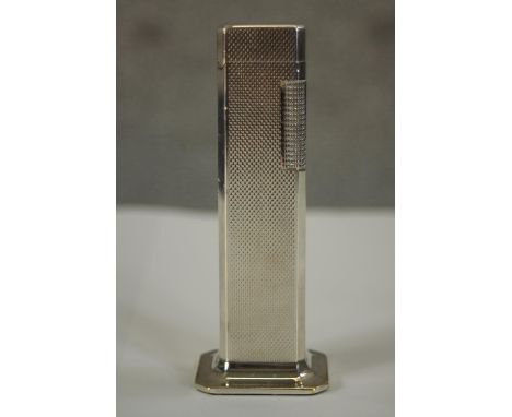 A 20th century silver plated table top Dunhill Tall Boy lighter with engine turned decoration, raised on shaped plinth lighte