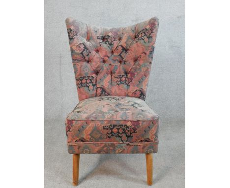 A mid 20th century light beech button back nursing chair, raised on out splayed supports. 
