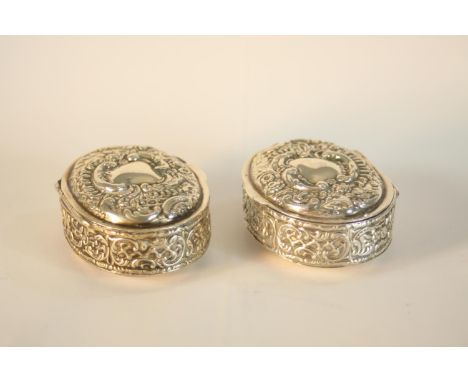 A pair of Edward VII hallmarked silver oval trinket boxes, Birmingham 1902, each with repousse scroll decoration and plain ro
