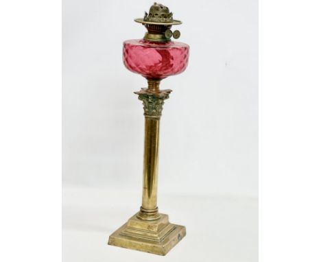 A large Victorian Ruby glass oil lamp with brass Corinthian style column. 60cm 