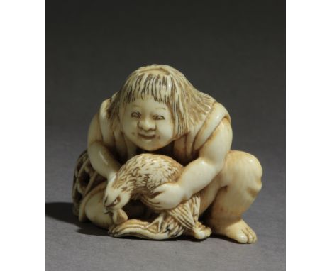 A late 19th century Japanese netsuke from Meiji period. In carved elephant tusk portraying Kintaro sat on the floor and grabb