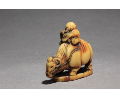 A Japanese netsuke from Edo period circa 1800. In carved elephant tusk portraying 'Ushidoji' sat on his ox's back, while play