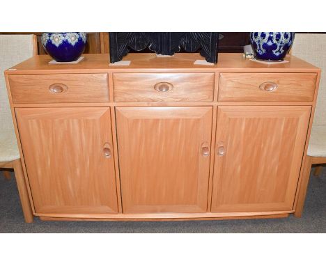 An Ercol light elm Windsor sideboard, with three drawers over three cupboard doors, 155cm by 44cm by 94cm, together with a ma