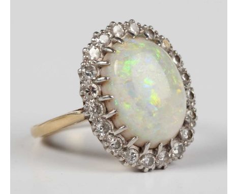 An 18ct gold, platinum, opal and diamond oval cluster ring, claw set with the oval opal within a surround of circular cut dia