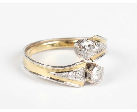 A gold, platinum and diamond ring in a crossover design, claw set with two principal transitional cut diamonds between gradua