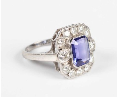 An 18ct white gold, tanzanite and diamond cluster ring, collet set with the cut cornered rectangular step cut tanzanite withi