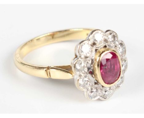 An 18ct gold, ruby and diamond cluster ring, collet set with the oval cut ruby within a surround of ten circular cut diamonds