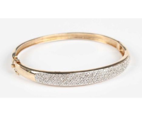 A gold and diamond oval hinged bangle, the front mounted with circular cut diamonds, on a snap clasp, detailed ‘DIA 050 375’,