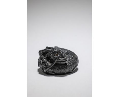 NETSUKE EN ÉBÈNE REPRÉSENTANT UN DRAGONPar Hoei, XIXe siècleAN EBONY NETSUKE OF A DRAGONBy Hoei, 19th centuryThe three-clawed