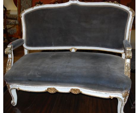 An early 20th century French white painted and parcel gilt two-seat salon sofa, having scroll carved arms of squat cabriole s