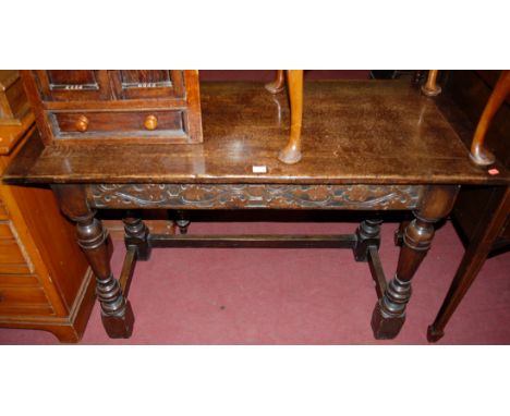 An 18th century style oak side table having a rectangular planked top above a carved single frieze drawer on turned supports