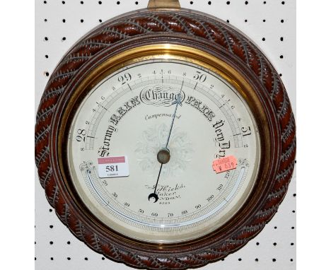 An early 20th century barometer of circular form, with silvered dial signed J Hicks maker of London, in an oak ropetwist surr