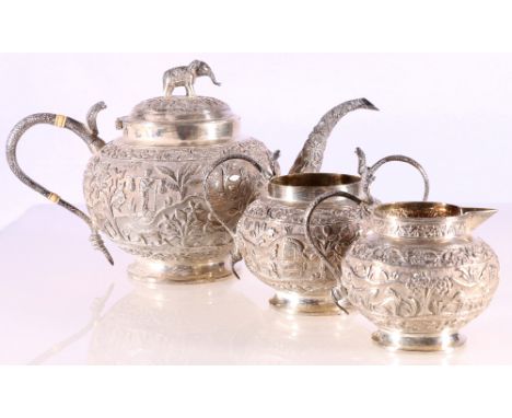 Indian white metal three piece teaset, chased and engraved with natives on foliate landscapes, the teapot with elephant finia