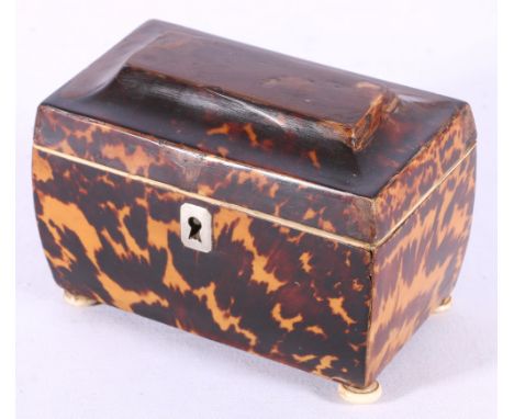 Georgian tortoiseshell tea caddy of sarcophagus form, white metal escutcheon, on four ivory bun feet, the interior with two l