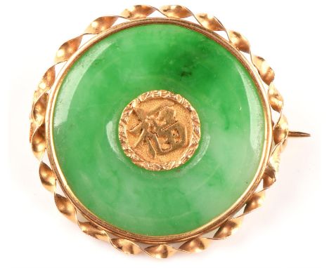 Four brooches, including an oriental jade brooch tested 22 ct, measuring 32cm in diameter, a shell cameo brooch with safety c