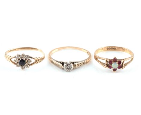 Three gem set rings, one sapphire and paste daisy ring in a split shoulder mount, ring size M, a ruby and opal cluster ring w