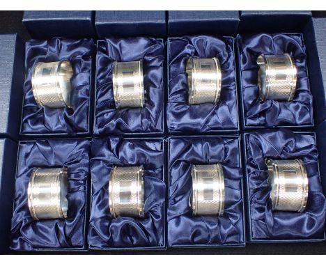 A SET OF EIGHT ENGINE-TURNED SILVER NAPKIN RINGS individually boxed