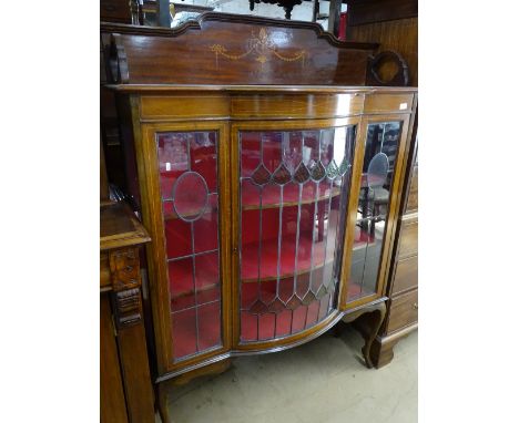 A late Victorian mahogany bow-front display cabinet, having leadlight glazed panels, floral marquetry inlaid decoration, widt