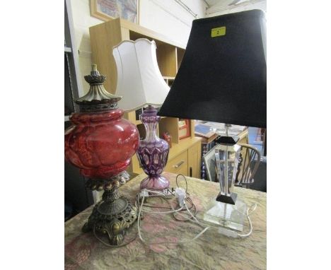 Three table lamps to include an amethyst and clear overlaid and cut glass lamp, a black and clear faceted lamp and a brass an