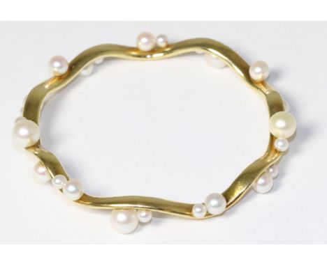 An 18 carat gold cultured pearl bangle, inner diameter measures 6.7cm The bracelet is in good condition. It is hallmarked wit