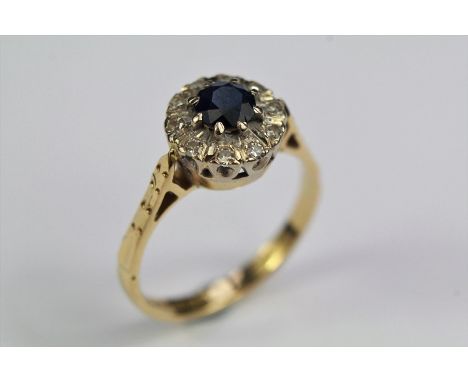 A Vintage 18ct Sapphire and Diamond Ring. The ring having a midnight blue sapphire approx 4.5mm surrounded by approx 15 pts o