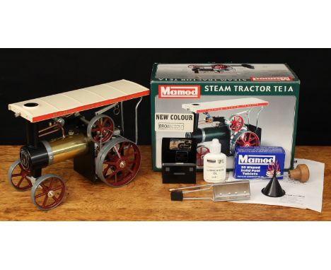 A Mamod TE1A live steam tractor, gold body with cream canopy, brown spoked wheels and flywheel, boxed with steering rod, scut