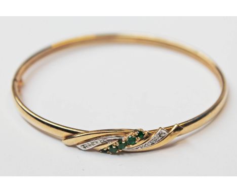 A 9ct gold diamond emerald bangle, diam. 6cm, gross wt. 7.3g.