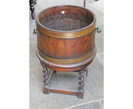 A 1920s brass bound oak barrel planter on stand by R A Lister & Co. Diam. 47cm H56cm.