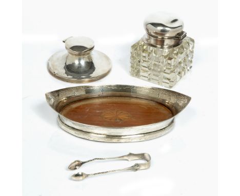 Glass inkwell with silver mounted lid, a silver cap stand inkwell, a silver boat shaped dish with inlaid base and a pair of s