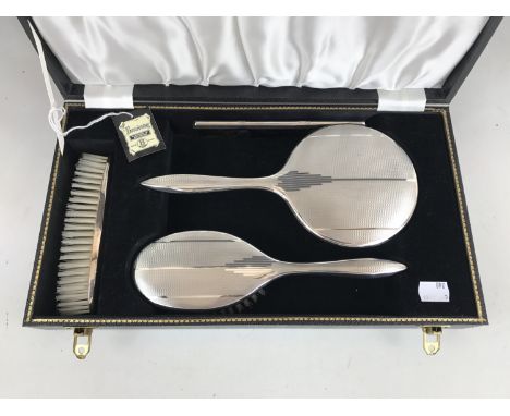 An Elizabeth II cased silver four-piece dressing table set, comprising hand mirror, hair brush, comb and clothes brush, each 