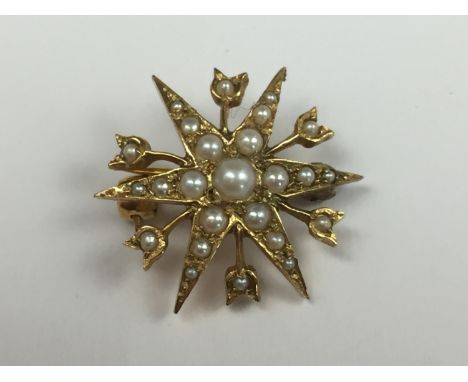 An antique 9ct gold and seed pearl brooch modelled in the form of a star burst, the points being interspersed by radiating bl