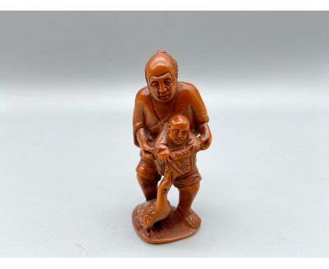Japanese hand carved netsuke of a gentleman holding a child within a basket, signed by the artist [5.5cm] 
